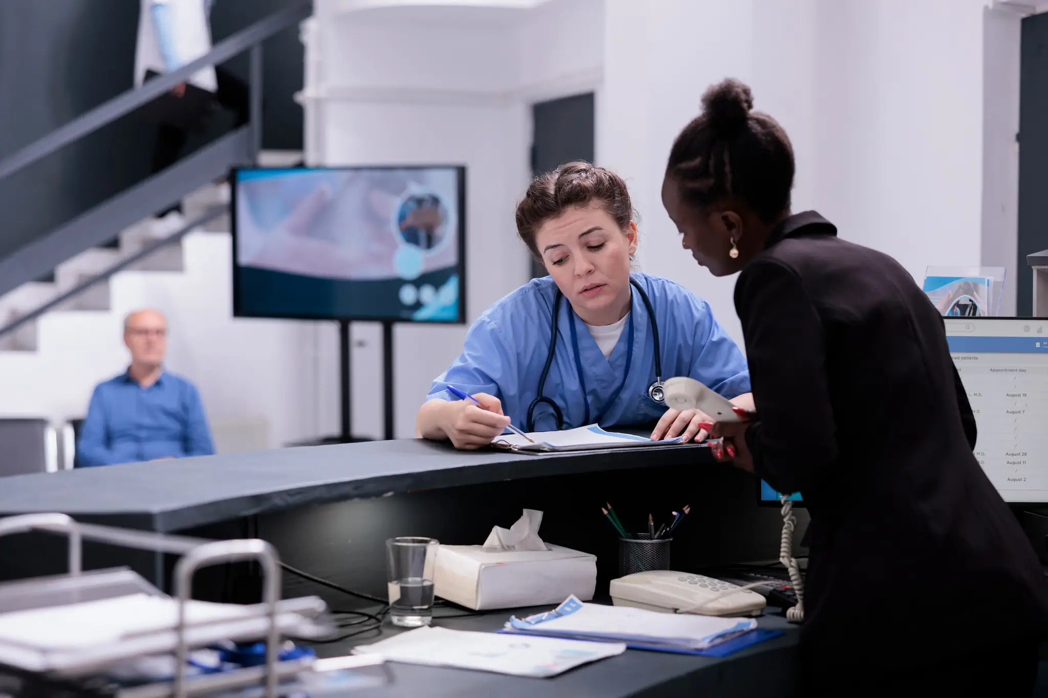 Medical reception staff reviewing a patient report in a clinic lobby